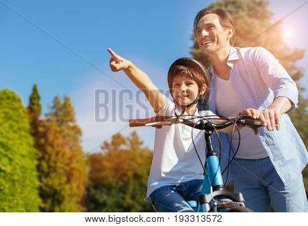 Dad, look. Enthusiastic bright lively kid spending an active day with his parent and suggesting they taking a ride somewhere