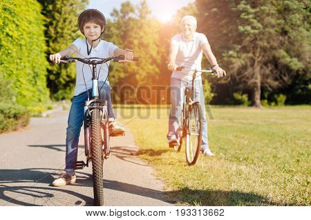 Dream weekend. Lively passionate cute boy and his grandpa having some rest while enjoying an active weekend and riding bicycles together
