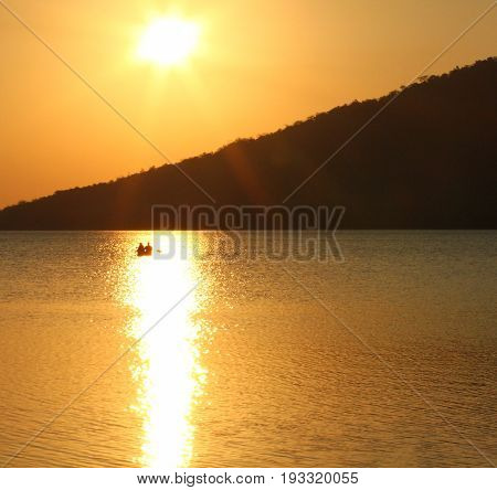 A sunset with the silhouette of a little local fisher boat on Peten Itza with a rising hill on the background. Lake Peten Itza is located in north Guatemala near Flores.