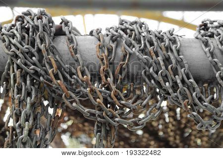 Pattern of thick rusty chain hang on iron rail.