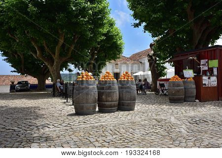 Obidos Portugal - June 1 2017: Heap of bright ripe oranges at the barrels on the small square of the medieval city of Obidos Portugal
