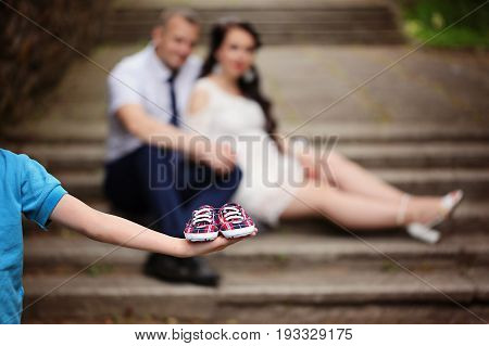 Little shoes on kids hand over background future parents. Concept of Parents-To-Be.