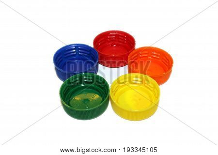 Bottlecaps in rainbow colors arranged in the shape of a flower. Isolated on white background.