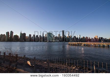Pier and fence at Gantry Plaza State Park and Manhattan under the shade