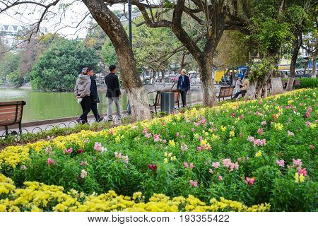 Hanoi Vietnam - Feb 20 2017 : Peopla walking by Flower Garden at Hoan Kiem Lake the center of Ha Noi Vietnam in the evening