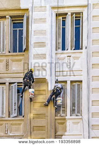 MONTEVIDEO, URUGUAY, JUNE - 2017 - Two workers hanging by cables painting the facade of apartment building in Montevideo Uruguay