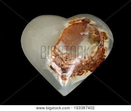 Polished multicolor carved onyx heart on black background