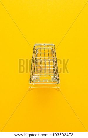 top view of shopping trolley. shopping trolley on yellow background. shopping trolley with some copy space. shopping trolley with yellow handle