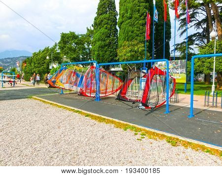 Torbole, Italy - September 21, 2014: Lake Garda beach with tourists and catamaran in Torbole, Italy. Torbole is one of the most popular towns on Garda Lake, known as a wind surfers paradise.