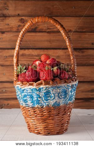 Strawberries in basket on wooden background, closeup