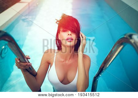 Sexy wet woman in swimsuit with big tits at summer in swimming pool