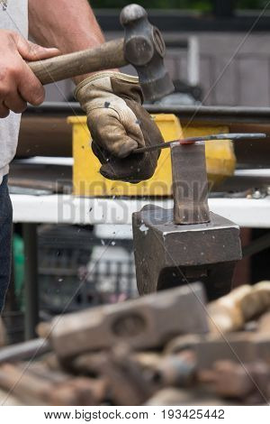 A blacksmith hammering hot iron during medieval fair festival in Streatham Park in London