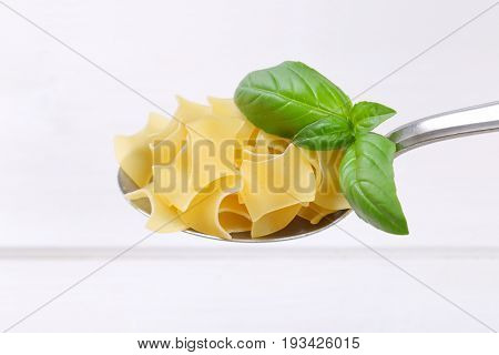 spoon of quadretti - square shaped pasta on white wooden background