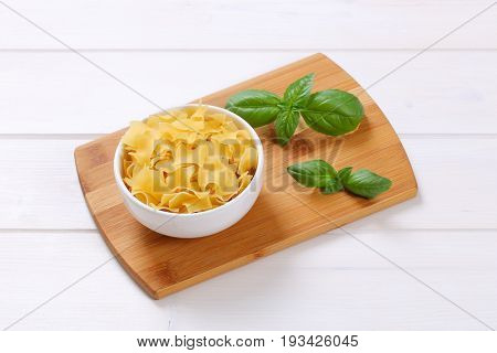 bowl of quadretti - square shaped pasta on wooden cutting board