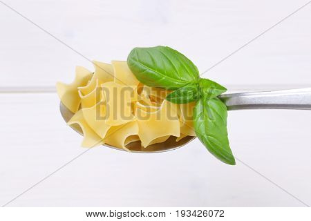 spoon of quadretti - square shaped pasta on white wooden background