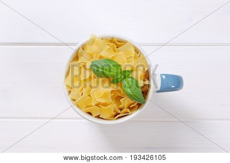 mug of quadretti - square shaped pasta on white wooden background