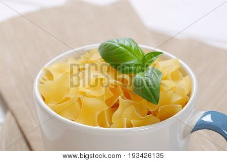 mug of quadretti - square shaped pasta on beige place mat - close up