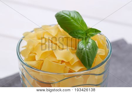 glass of quadretti - square shaped pasta on grey place mat - close up