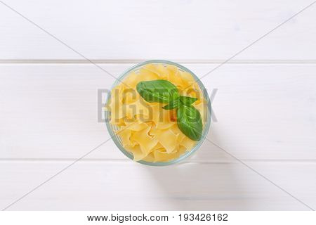 glass of quadretti - square shaped pasta on white wooden background
