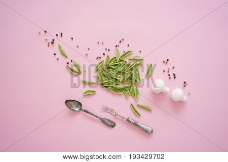 Dry green foglie pasta made from durum wheat semolina dried tomatoes spinach and water. Top view on old silver cutlery with champignons and pepper on pink background