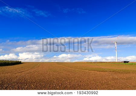 Field under a blue sky with nice clouds and a wind turbine. Bekkevoort Flanders Belgium