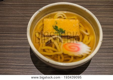 Kitsune Udon Japanese Noodles In White Bowl On Wooden Table