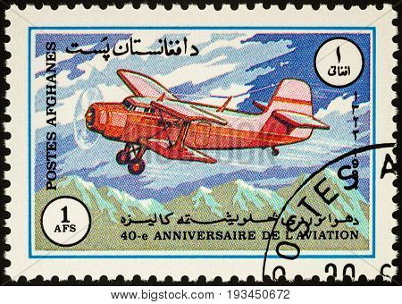 Moscow Russia - April 14 2017: A stamp printed in Afghanistan shows old flying aircraft (biplane) over mountains series 