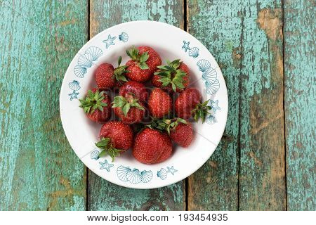 Organic heiroom ripe strawberries on turquoise table overhead view