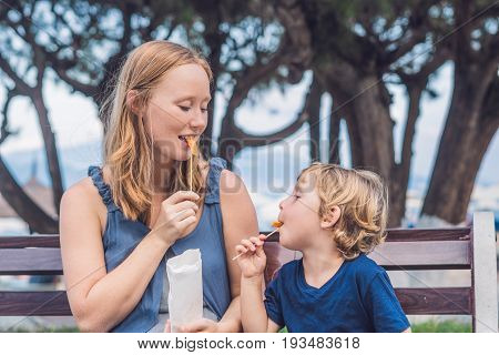 Mom And Son Eat Fried Sweet Potatoes In The Park. Junk Food Concept