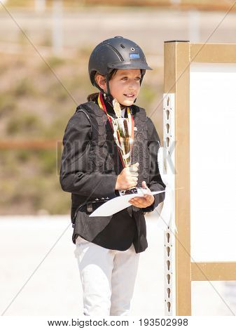 Young girl with cup and medal after winning equine competition