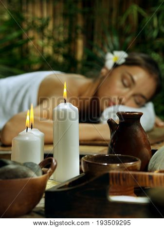 portrait of young beautiful woman in spa environment. focused on candles.