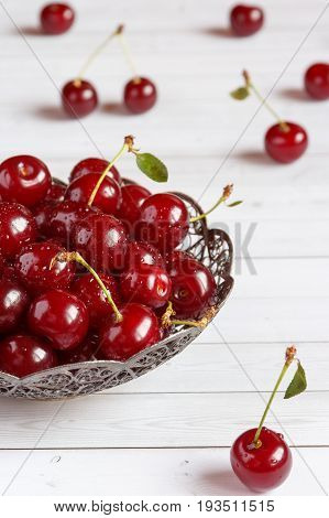Fresh cherry on plate on wooden background and fresh ripe cherries