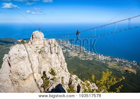 CRIMEA, RUSSIA - MAY 19, 2016: Tourist walking on a rope bridge on the Mount Ai-Petri. Ai-Petri is one of the highest mountains in Crimea and tourist attraction.