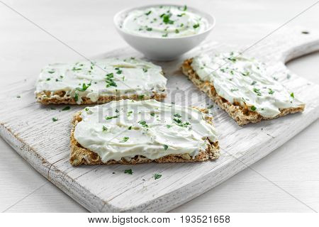 Homemade Crispbread toast with Cream Cheese and parsley on white wooden board background