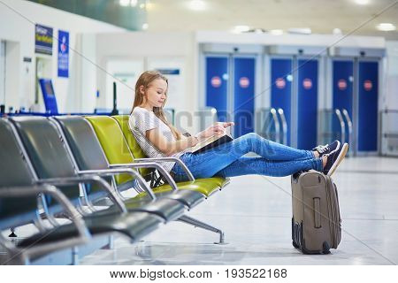 Young Travelerin International Airport Reading A Book While Waiting For Her Flight