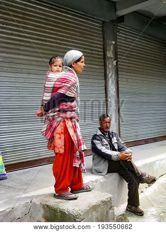 VILLAGE NAGGAR VALLEY KULLU STATE HIMACHAL PRADESH INDIA - APRIL 19 2014: Family is waiting on the platform for public transport in small village in Himalayas in north of state Himachal Pradesh.