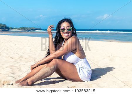 Colorful portrait of young attractive asian woman in sexy white dress on the tropical beach of Bali island.