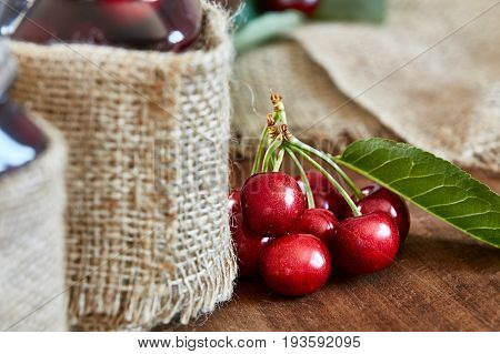 Cherry jam on wooden background in glass jars