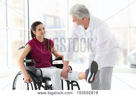 Young disabled woman with senior orthopedist in rehabilitation clinic
