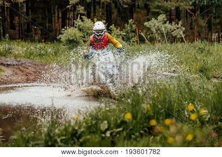 motorcycle enduro crosses puddles of water and mud in forest