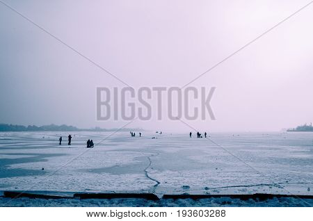 Winter on the lake. Frozen lake. People enjoy on frozen lake on cold misty day. Palic lake, Serbia.