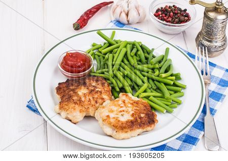Lunch from green beans and cutlets on white wooden table. Studio Photo