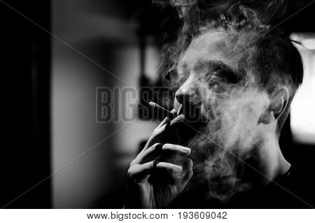 Cigarette addict. Person smoking cigarette. Black and white. Hard contrast. With film grain. Cigarette smoke. Addiction.