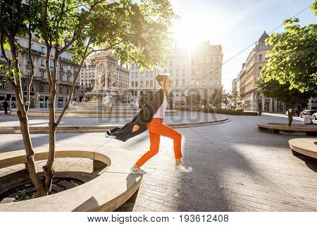 Lifestyle portrait of a stylish woman jumping on the Jacobins square in Lyon city