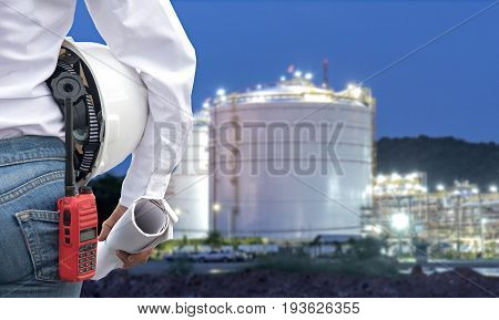 Engineer woman holding white helmet and blueprint with radio for workers security control at power plant energy industry. Engineer Concept
