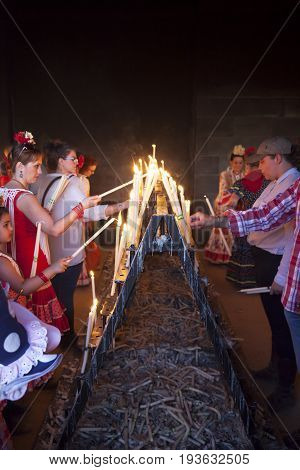 El Rocio Spain - June 2 2017: Pilgrims in traditional spanish dress light up candles in the hermitage of El Rocio during the Romeria 2017. Andalusia Spain