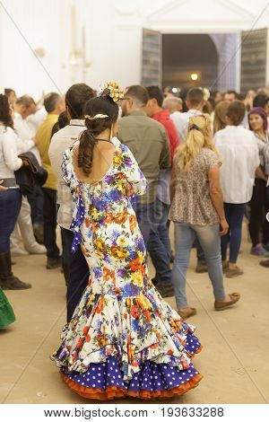El Rocio Spain - June 2 2017: Female pilgrim in traditional spanish flamenco dress in the hermitage of El Rocio during the Romeria 2017. Andalusia Spain