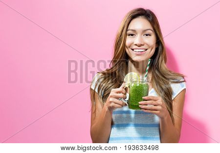 Happy young woman drinking smoothie on a solid color background