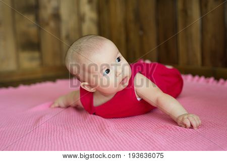 A little European-looking girl with big brown eyes lying on her belly with a keen eye