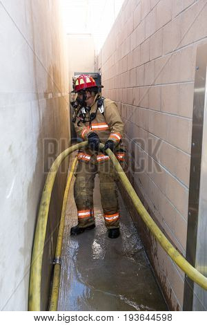 Firefighter Training Entering A Building With A Charged Hose